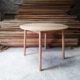 Pale wooden round table with round section legs that are slightly splayed out