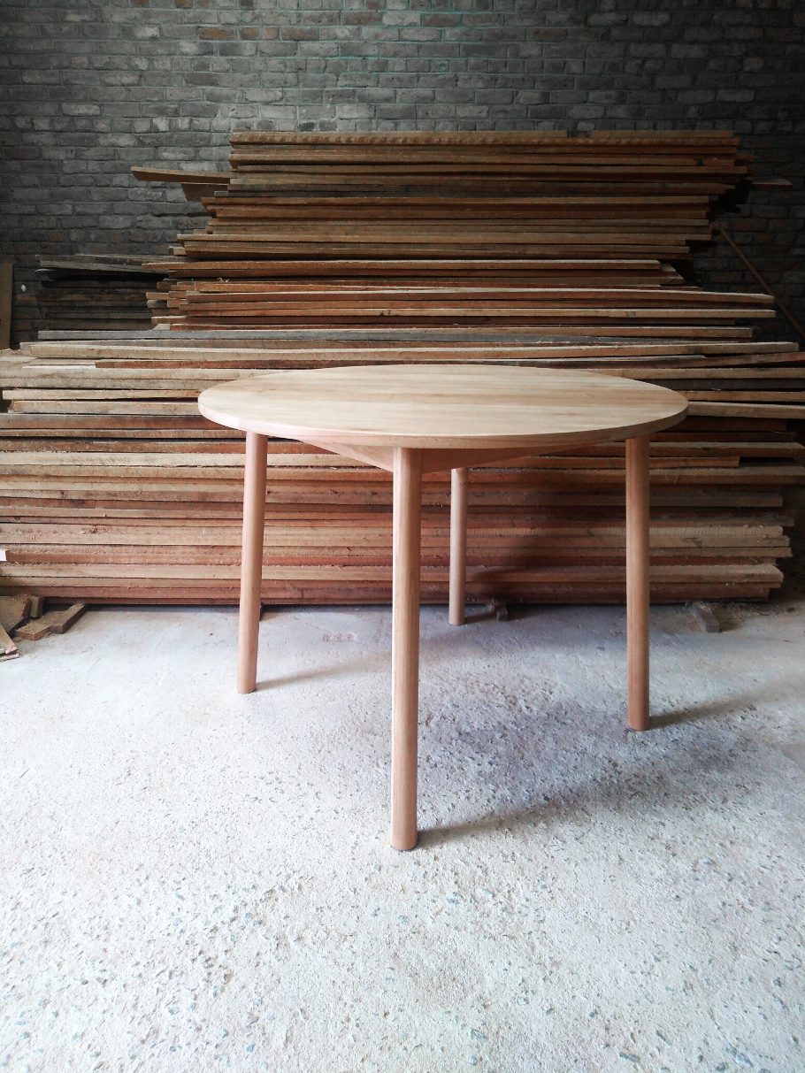 Pale wooden round table with round section legs that are slightly splayed out