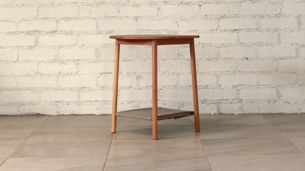 Wooden side table round section legs round top blueish grey fabric shelf