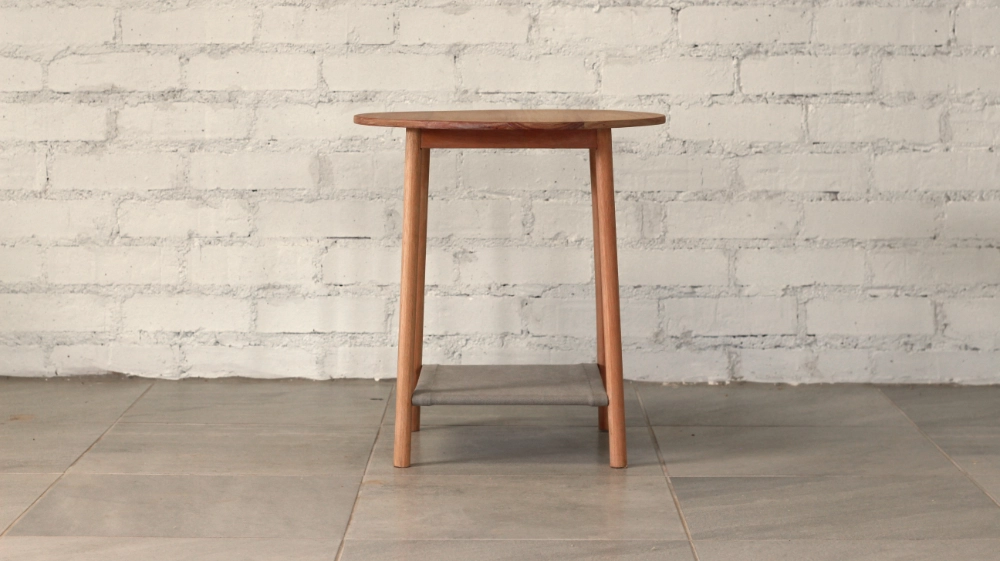 Wooden side table round section legs round top blueish grey fabric shelf