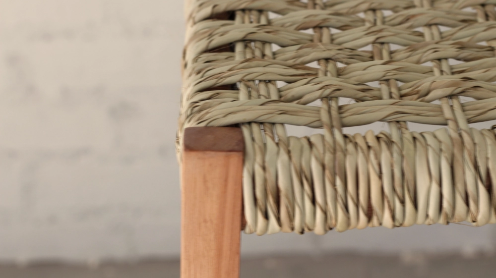 Wooden stool detail showing ilala palm woven seat and leg end grain detail.