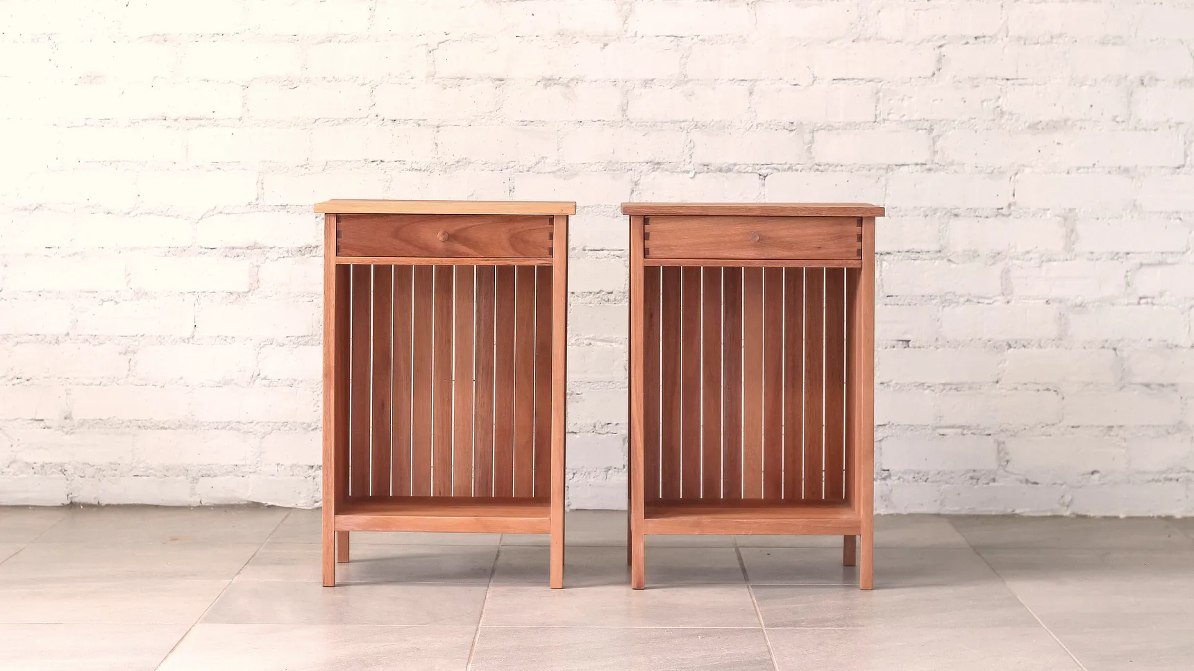 Two bedside tables made from pale brown timber with top drawers and open boxed storage.
