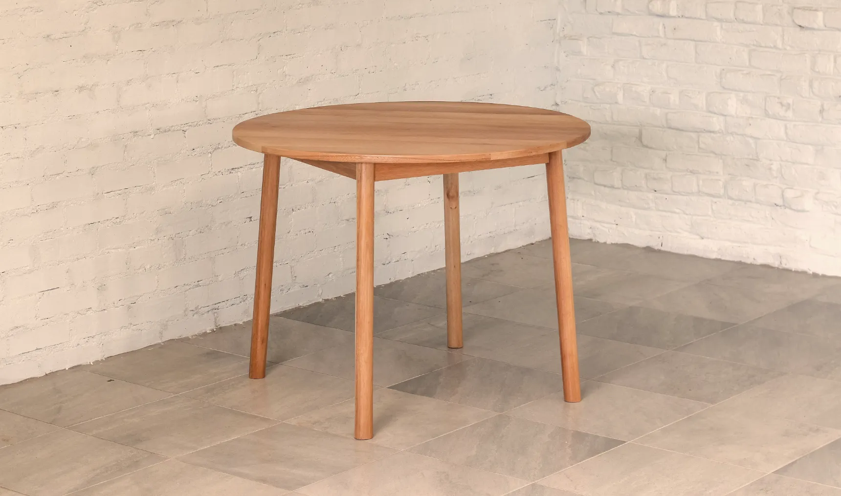 Round table made from pale brown timber with round section splayed legs.