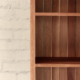 Detail of a bookcase made from a warm pale brown timber with hardwood slatted back panel.