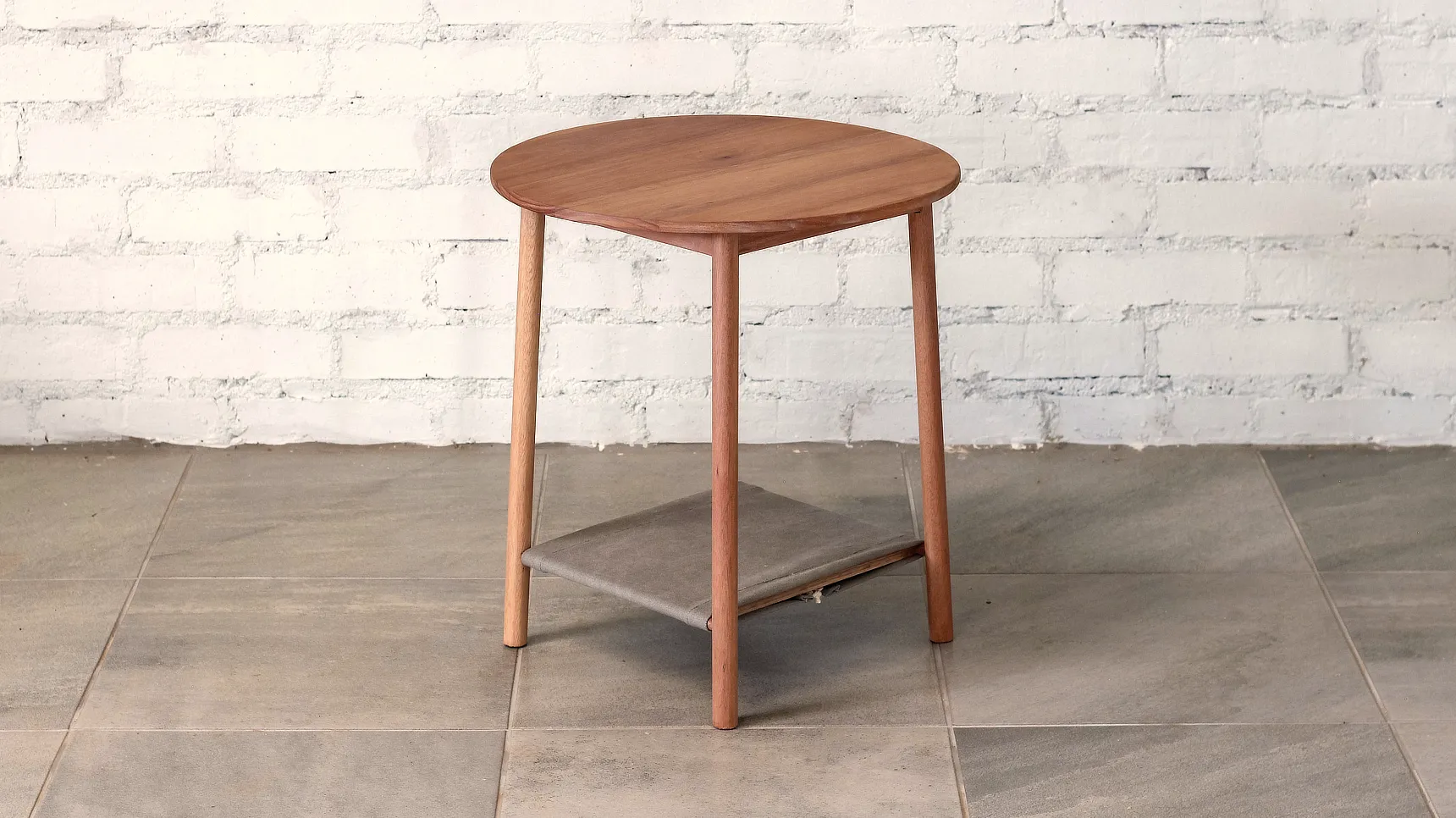 Side Table with round top, splayed round section legs and fabric shelf.