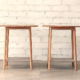 Two delicate round topped side tables with round section gently splayed legs and fabric shelves.