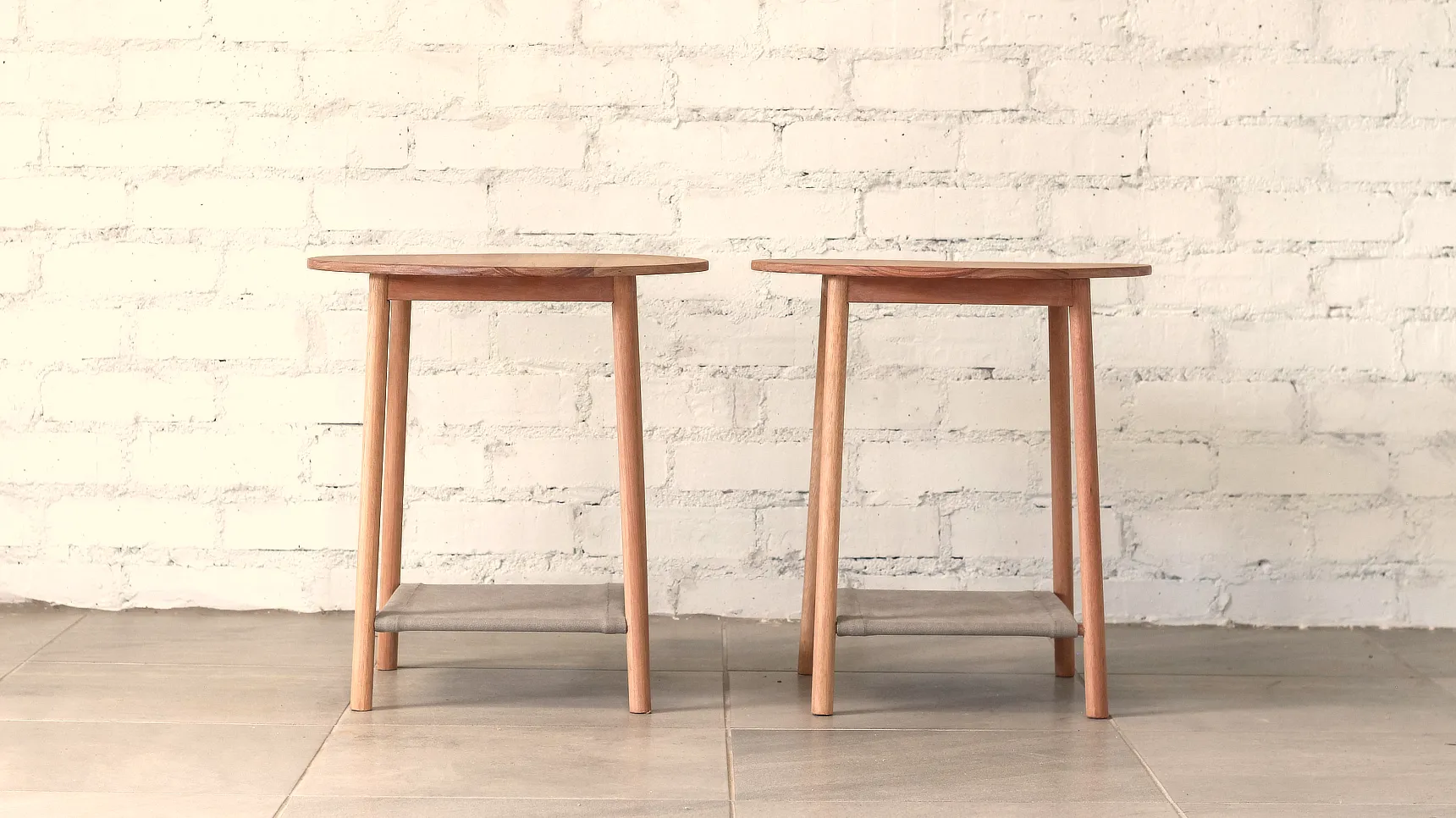 Delicate side tables with round tops, round section splayed legs and fabric shelves.