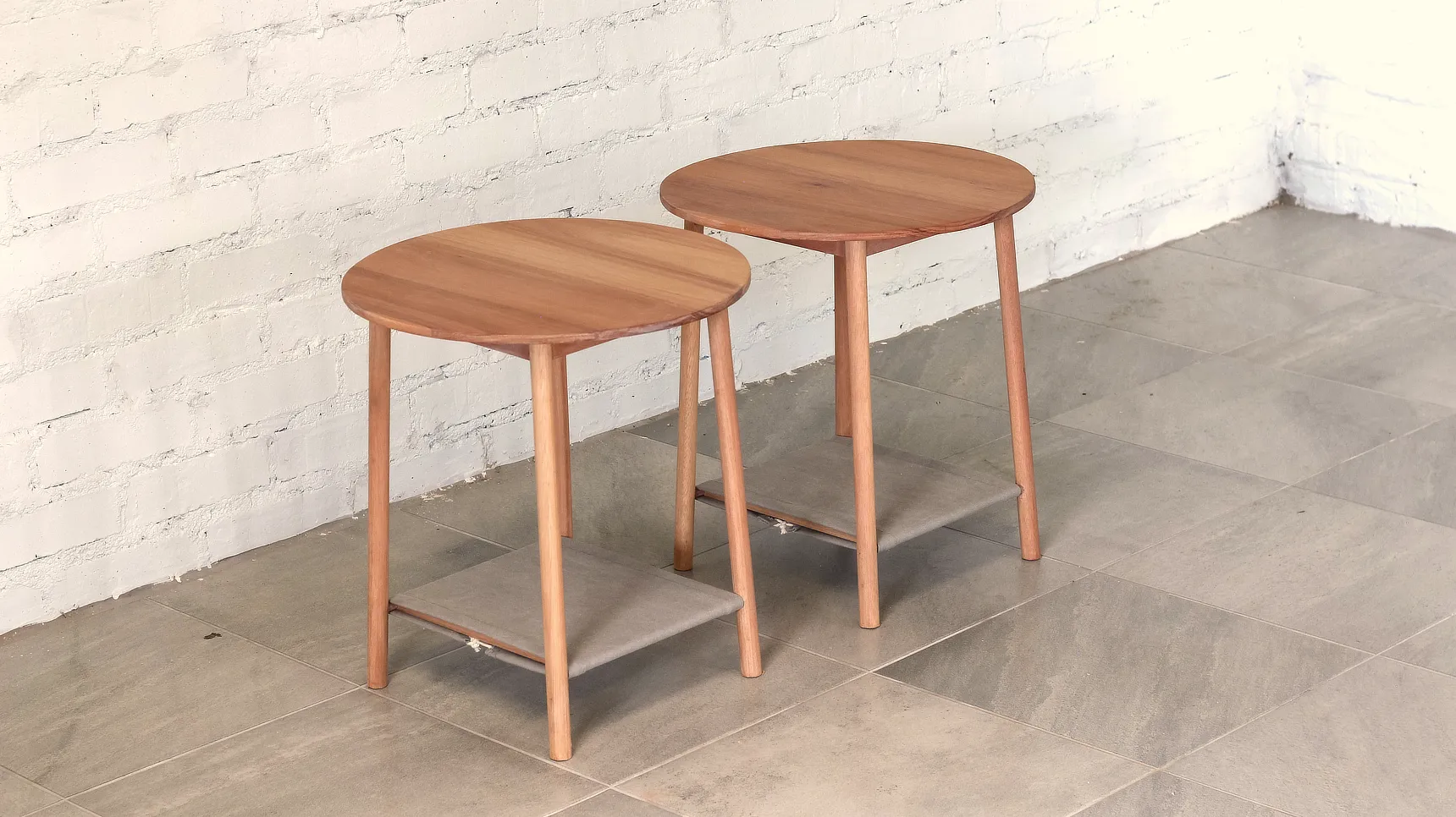 Delicate side tables with round tops, round section splayed legs and fabric shelves.