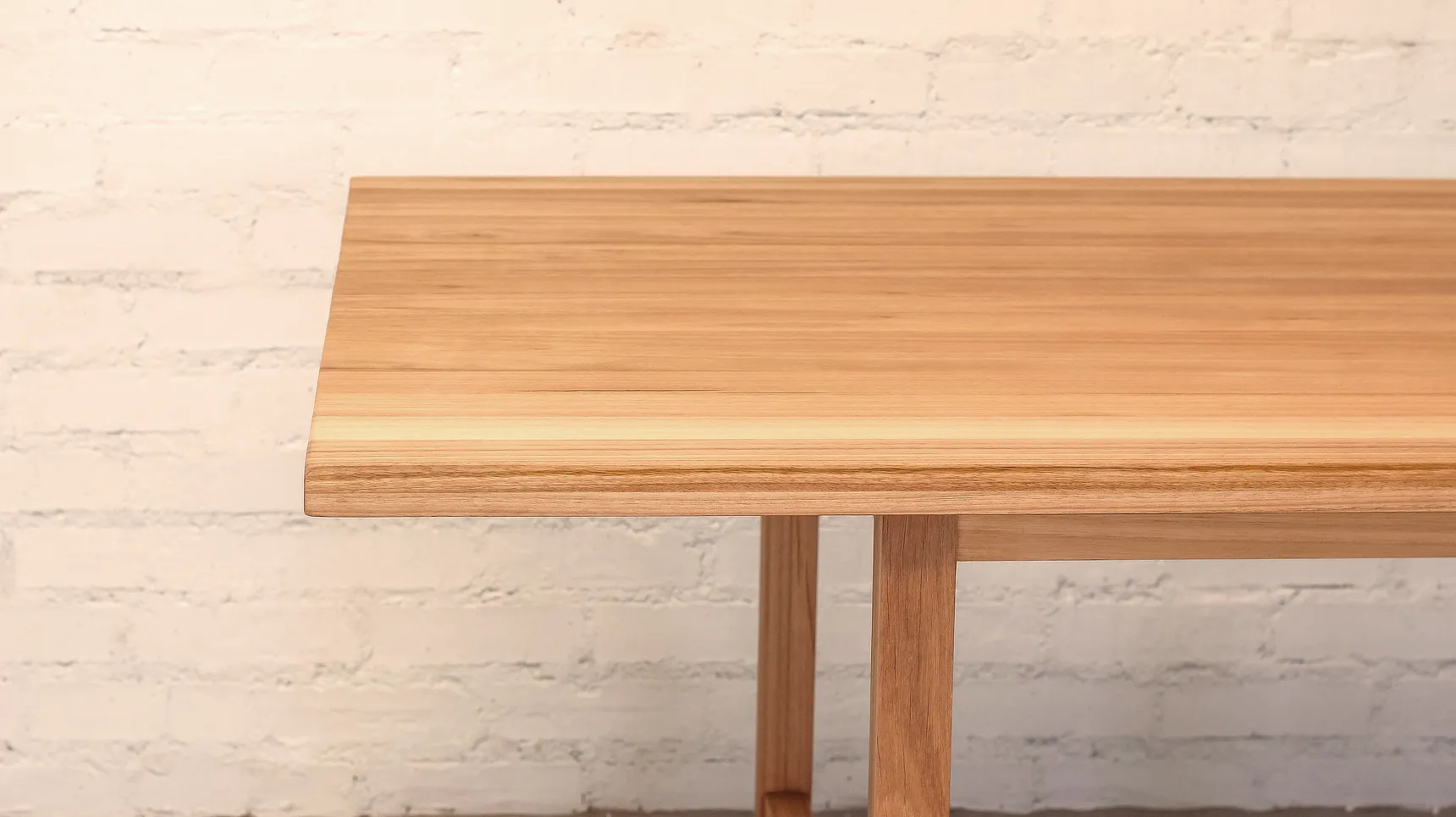 Detail of a linear wooden table made from a light textured timber.