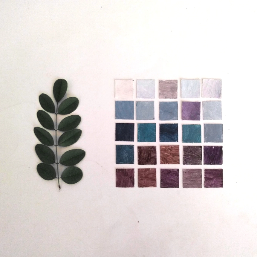 A photograph of a leaf on the left and a gridwork of small multi colored painted card tiles on the right.