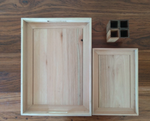 One large and one small tea tray made from pale timber and four pen holders.