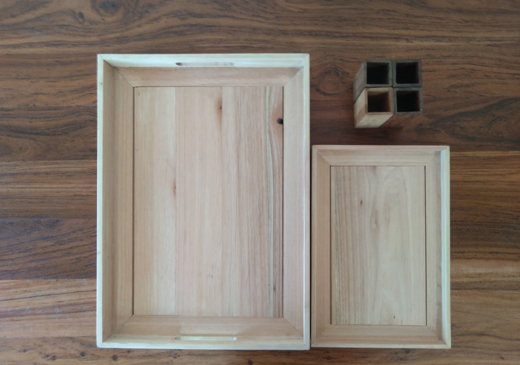 One large and one small tea tray made from pale timber and four pen holders.