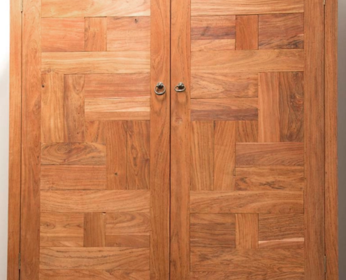 A detail from view of a teak wardrobe showing it's construction made up of panels made from small teak tiles alternating direction.
