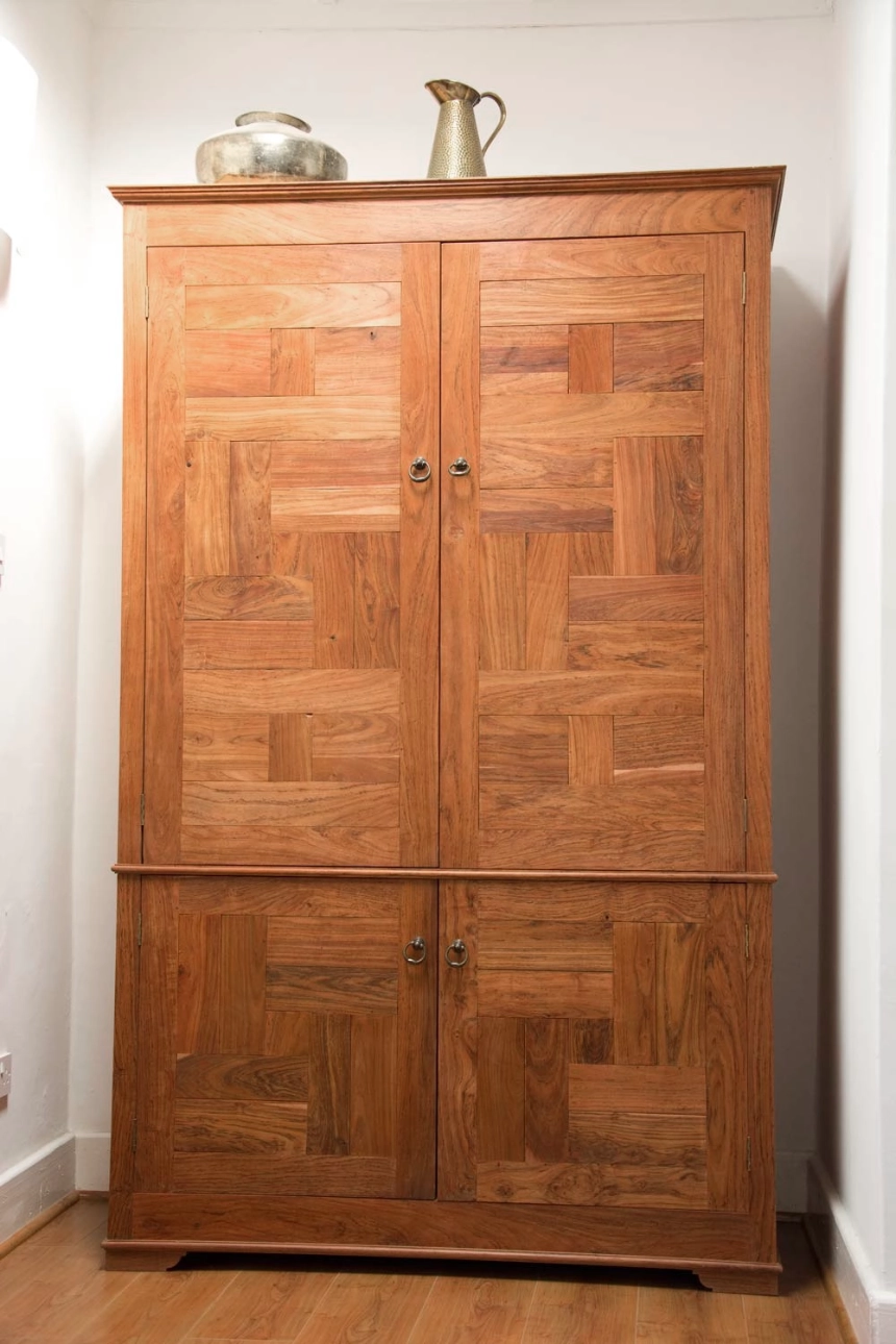 Wardrobe made up of panels made from small teak tiles with alternating direction. Spit into two sections with large doors and small doors.